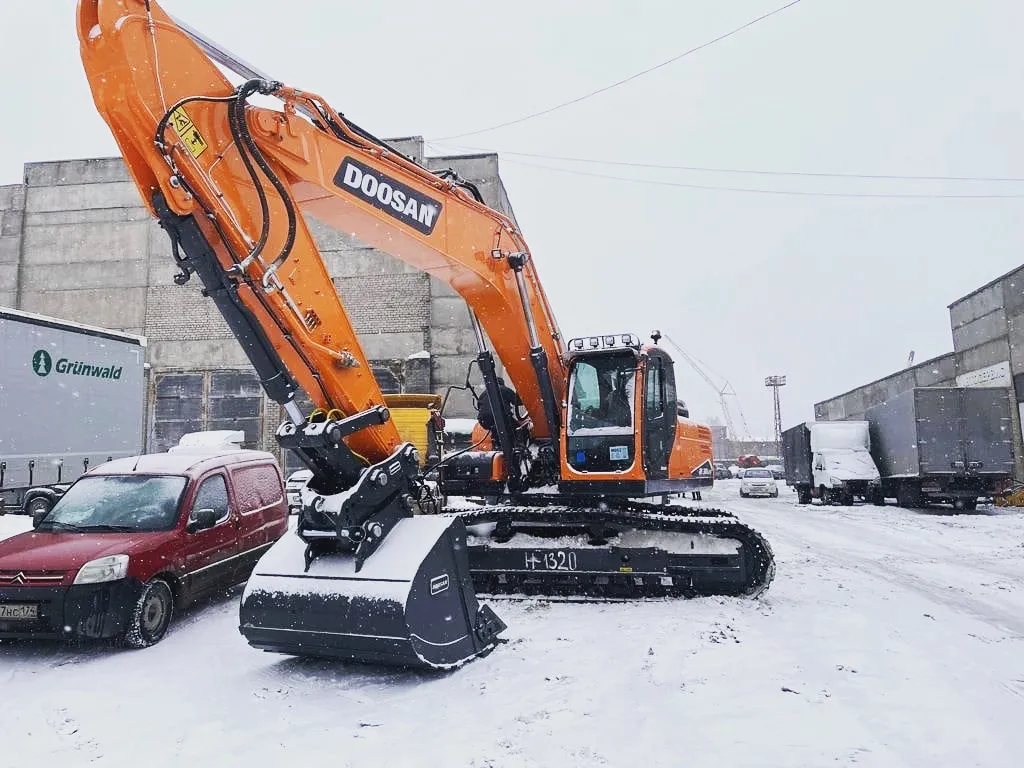 Гусеничный экскаватор Doosan с широким ковшом на заснеженной площадке