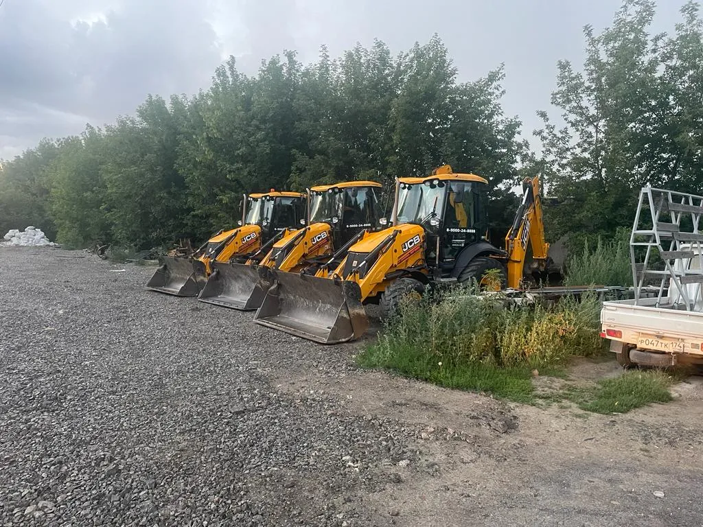 Три экскаватора-погрузчика JCB в ряд на стоянке