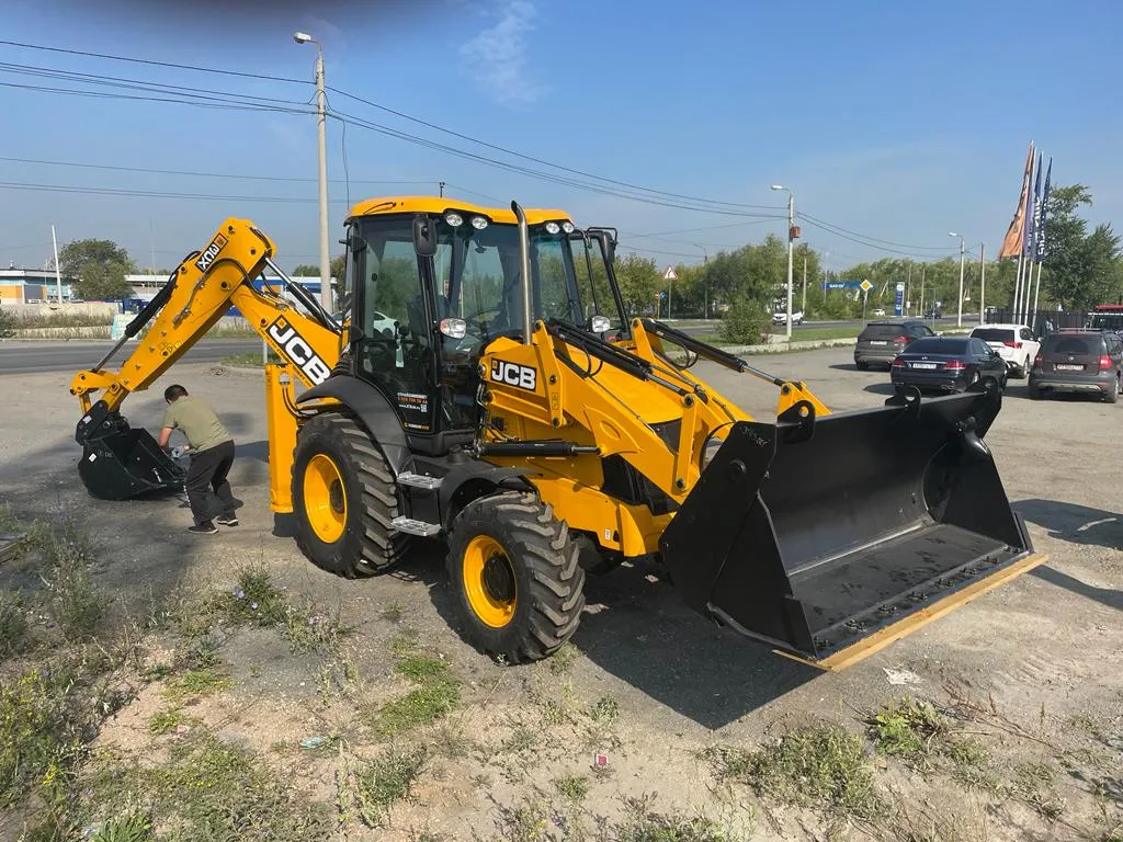 Экскаватор-погрузчик JCB с поднятым фронтальным ковшом, вид сбоку