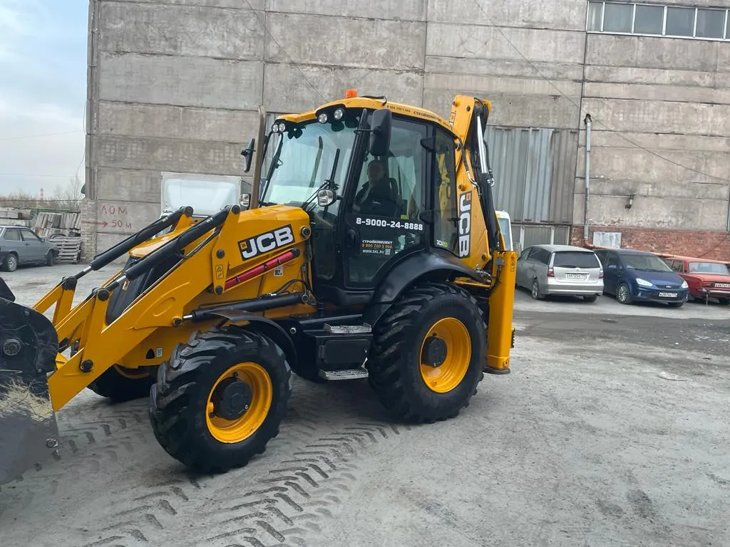 Экскаватор-погрузчик JCB у производственного здания